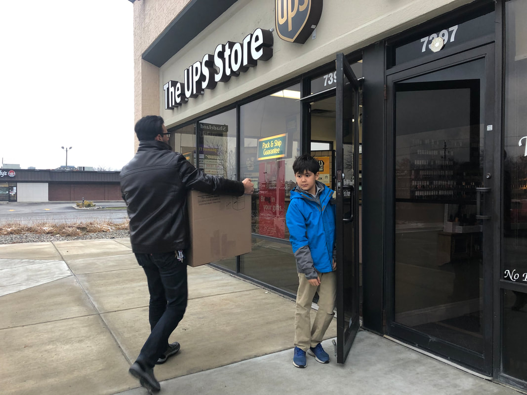 Yasseen and Mohamed delivering 2 boxes of shoes to the UPS Store to be shipped to Soles4Soles